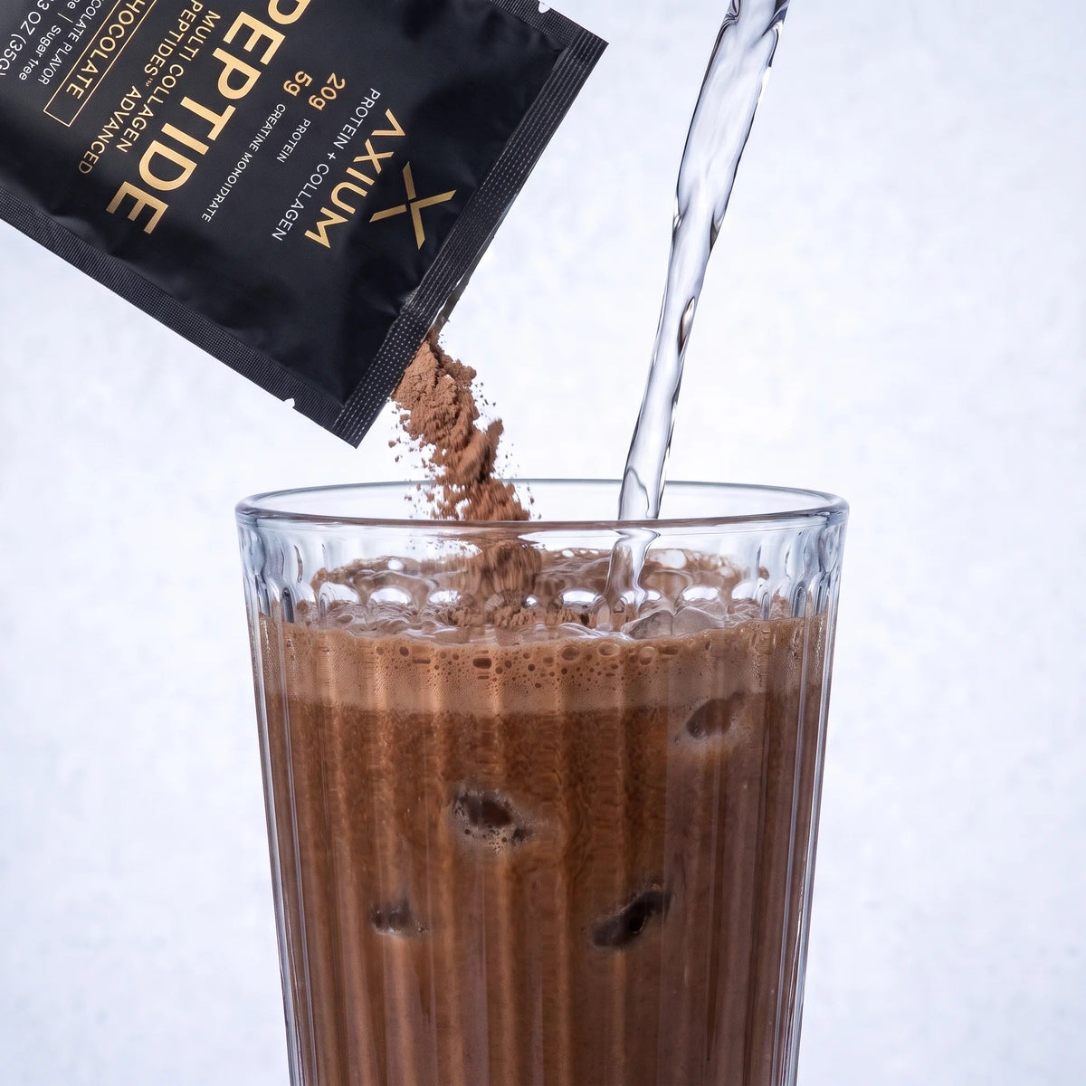Chocolate Axium Athletics powder poured into a glass of water